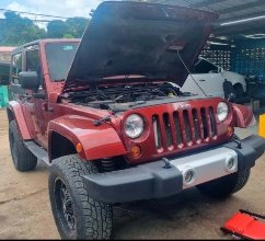 Jeep rojo en el taller con el capó abierto